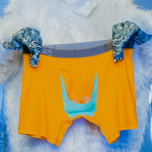 Yeti hands holding up marigold Shinesty cooling boxer briefs with a light blue Ball Hammock pouch on white fur