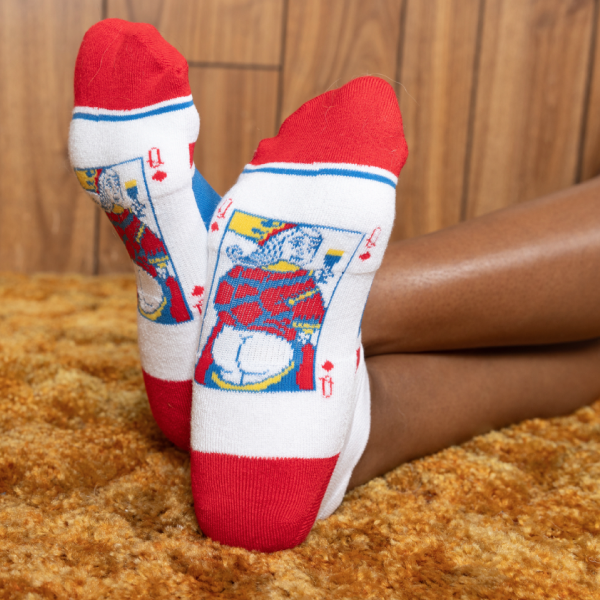 Crossed feet on a shag rug in white socks with red heels and toes and a playing-card king on each ankle