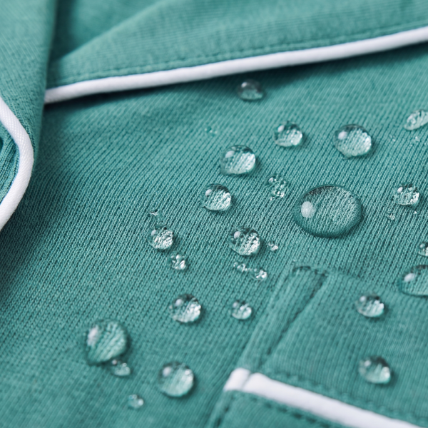 Green Shinesty pajama top with white piping and a chest pocket, water beads scattered across the fabric